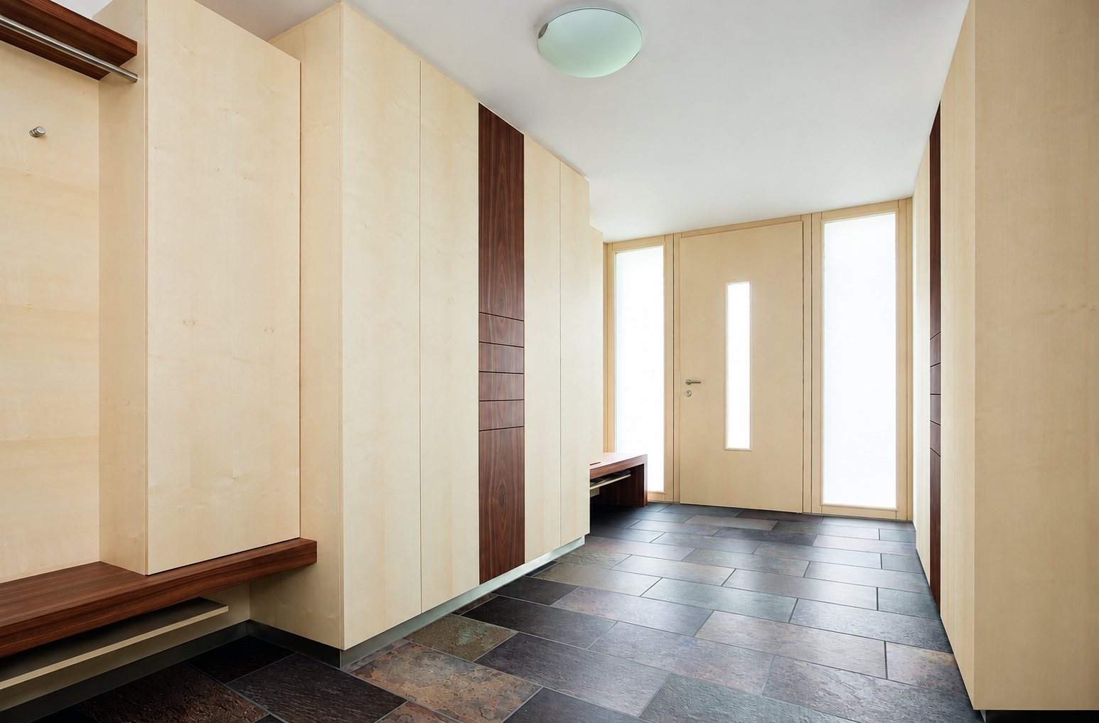 Vestibule lumineux aux placards en érable clair avec bandes en noyer, banc en bois, porte d'entrée vitrée et sol en dalles d'ardoise.